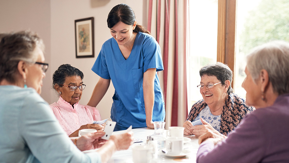 residents playing cards with nurse watching