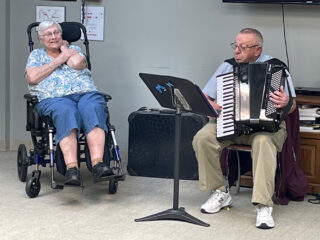 Gene plays the accordion while Val watches