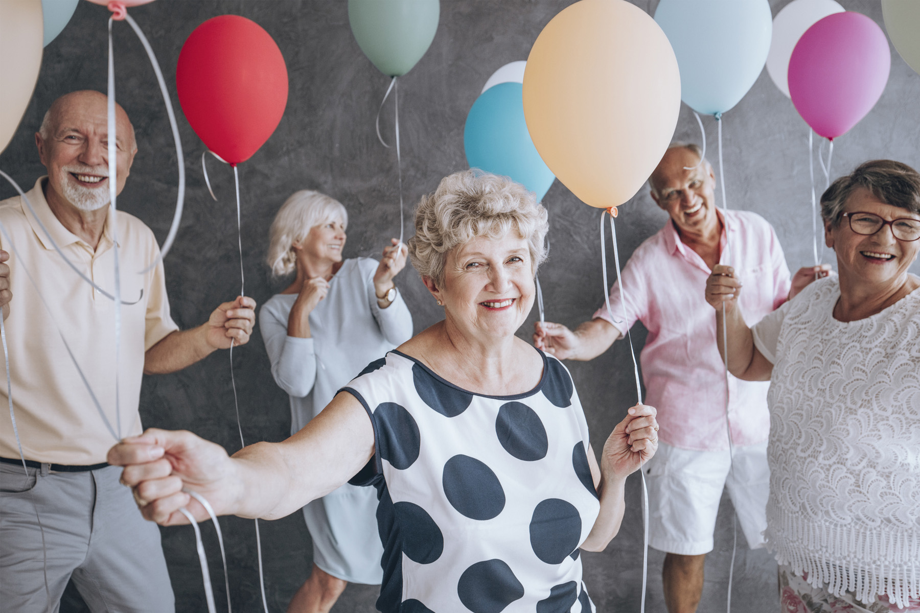 Seniors celebrating with colorful balloons, smiling and enjoying a festive gathering.