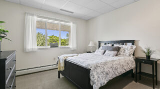 Bedroom with bed, dresser, and window at Apple Valley Village.