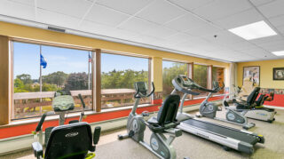 Fitness center with treadmills and cardio equipment near large windows at Apple Valley Village.