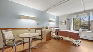 Health care bedroom with bed and seating at Apple Valley Village.