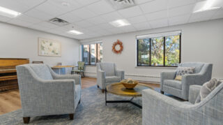 Health care center living room with seating and piano at Apple Valley Village.