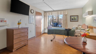 Resident room with bed and furnishings at Apple Valley Village.