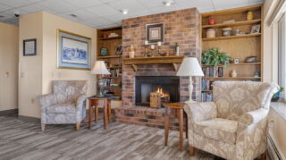 Cozy lobby seating area with brick fireplace and comfortable chairs at Apple Valley Village.