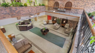 Overlook view of lobby seating area at Apple Valley Village with fireplace, lounge furniture, and open atrium layout.