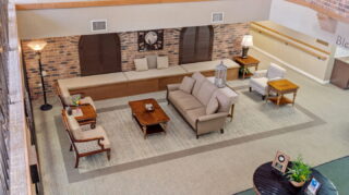 Lobby seating area at Apple Valley Village with sofas, chairs, and central coffee table for resident gathering.