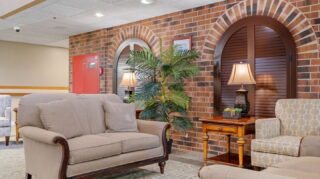 Cozy lobby seating area with brick fireplace and comfortable chairs at Apple Valley Village.