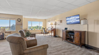 Memory care living room with seating and television at Apple Valley Village.