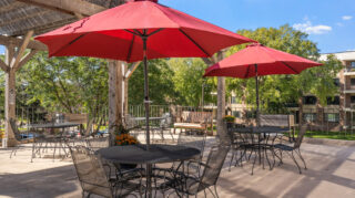 Outdoor patio seating with red umbrellas at Apple Valley Village senior living community.