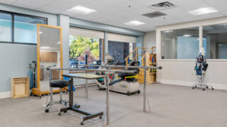 Therapy room with parallel bars and equipment at Apple Valley Village.