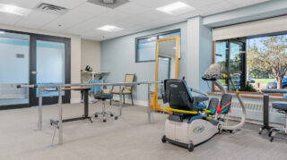 Therapy room with parallel bars and exercise equipment at Apple Valley Village.